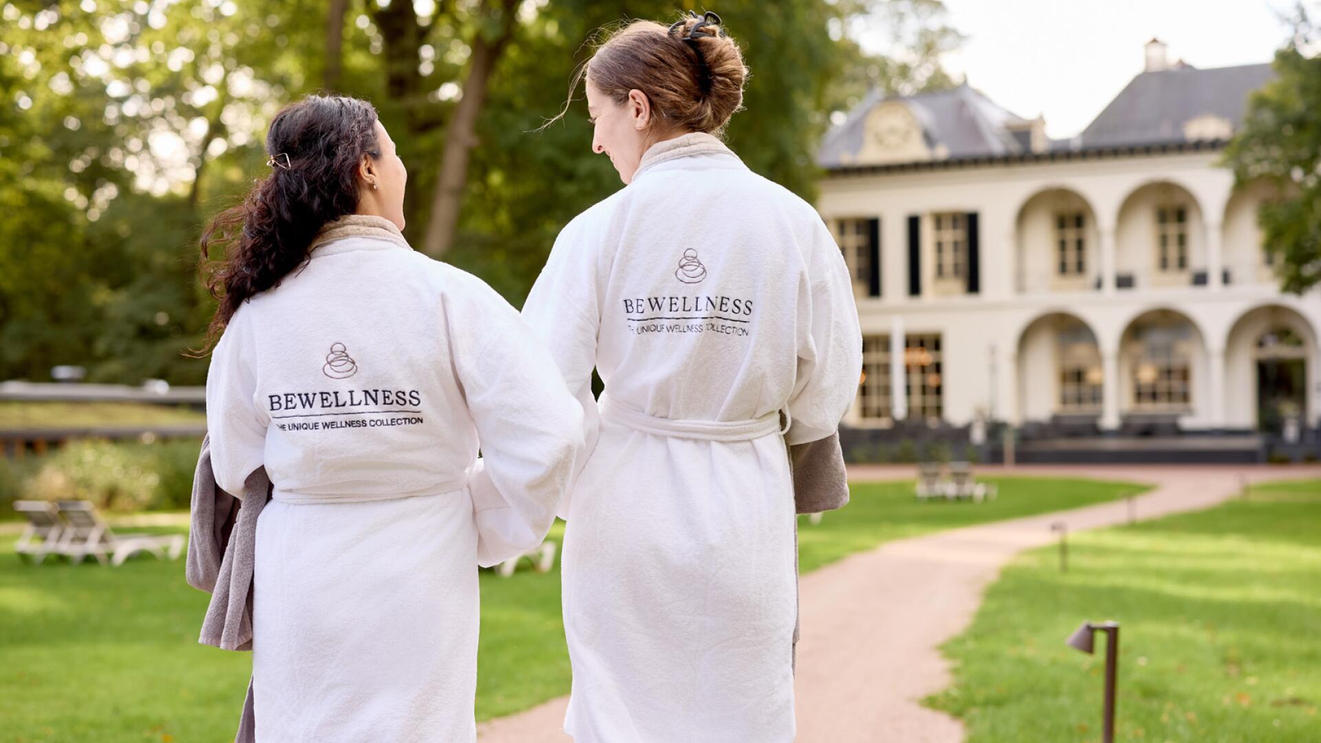 Twee vrouwen wandelen door de tuin van wellnessresort de Valkenberg